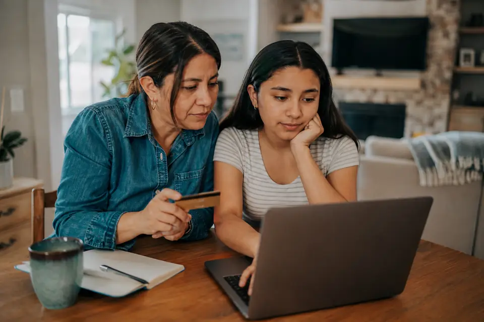 Madre e hija comparan cuentas bancarias en una computadora portátil en casa