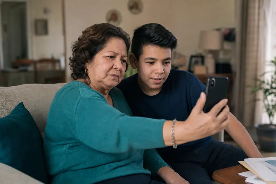 Señora mira con desconfianza una llamada sospechosa en su teléfono junto a su nieto