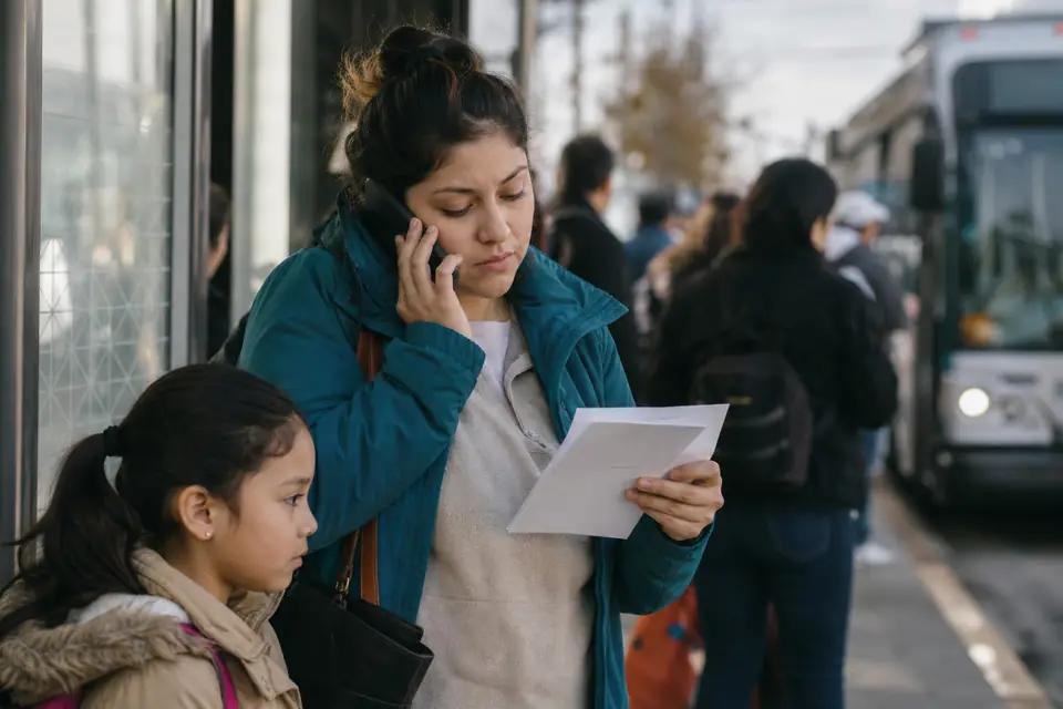 Mujer joven en parada de autobús revisa sobres y habla por teléfono